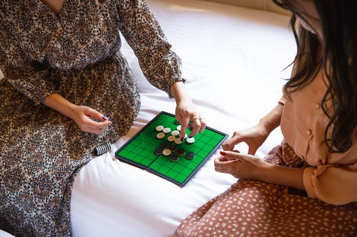 播种无法识别的女人在床上玩黑白棋游戏 · 免费素材图片