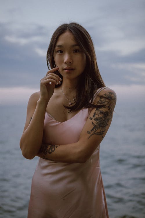在日落时分在海边休息的平静年轻时髦亚洲女人 · 免费素材图片