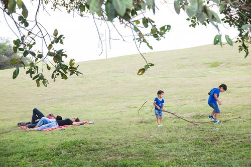 孩子们在草山上的匿名休息父母附近玩耍 · 免费素材图片