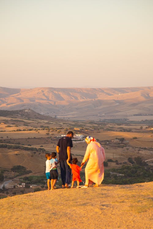 无法识别的穆斯林家庭站在山顶上，欣赏高地景观 · 免费素材图片