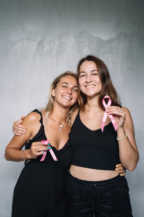 2名妇女微笑着拿着粉红丝带 · 免费素材图片