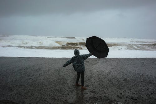 伞在风暴中岸上的人 · 免费素材图片