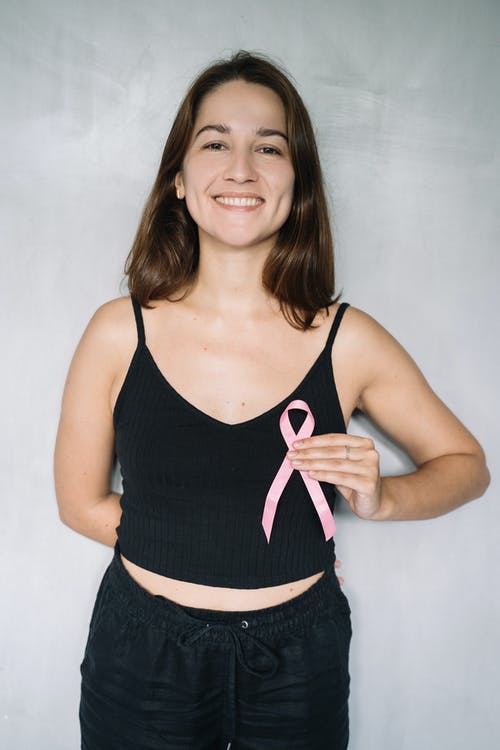 黑色背心抱着粉红丝带的女人 · 免费素材图片