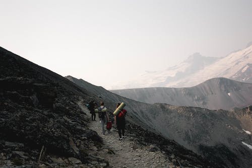 无法识别的旅行者在岩石斜坡上行走 · 免费素材图片