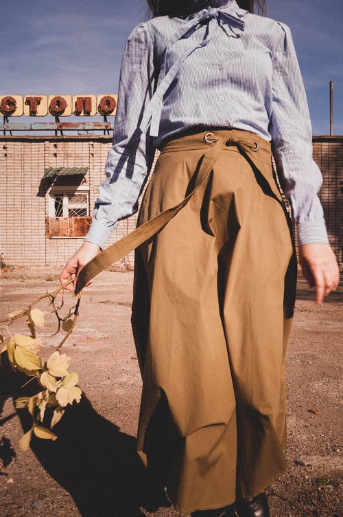 拿着白色和黑色棍子的棕色裙子的女人 · 免费素材图片