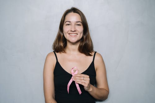 黑色的意大利面条皮带顶部拿着粉红丝带的女人 · 免费素材图片