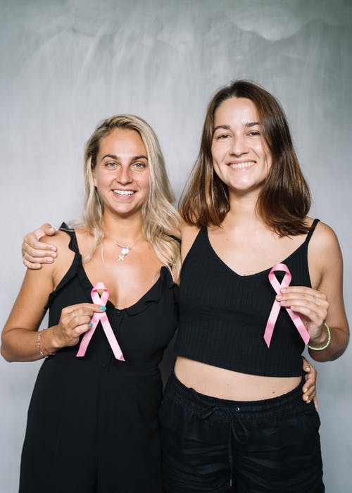 2妇女在黑色背心抱着粉红丝带 · 免费素材图片