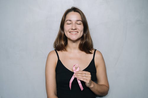 黑色的意大利面条皮带顶部拿着粉红丝带的女人 · 免费素材图片