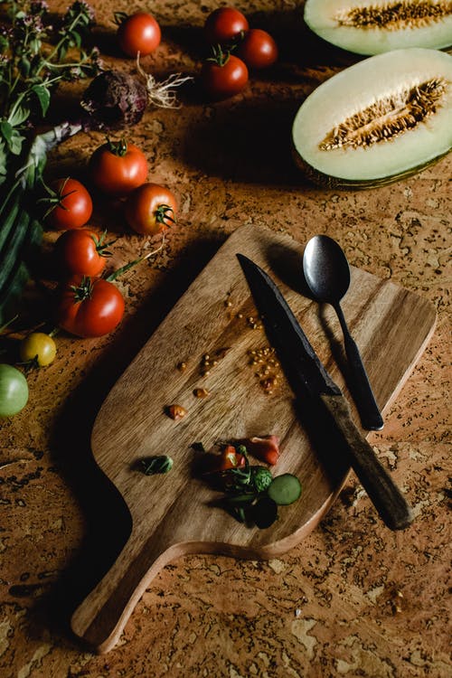 棕色木菜板上不锈钢叉旁边的红番茄 · 免费素材图片