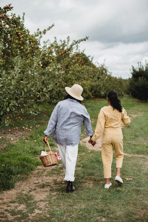 母亲和女儿在苹果树附近一起散步 · 免费素材图片