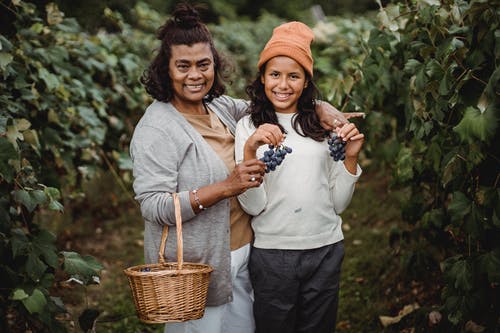 幸福的民族女人拥抱少年与成捆的成熟葡萄 · 免费素材图片