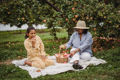 族裔母亲和女儿在树枝下野餐 · 免费素材图片