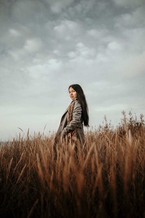 女人站在棕色的草地上 · 免费素材图片