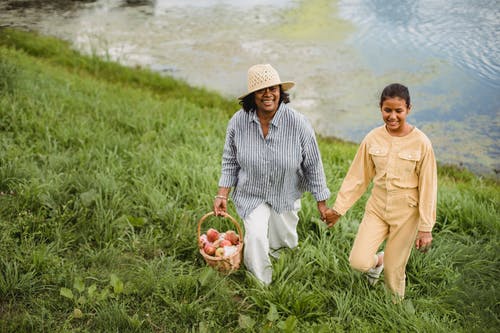微笑民族园丁带着女儿在草山上行走 · 免费素材图片
