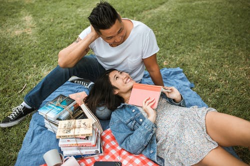 男人和女人坐在地上看书 · 免费素材图片