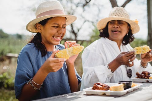 族裔有趣的女孩和妈妈一起在后院吃饭 · 免费素材图片