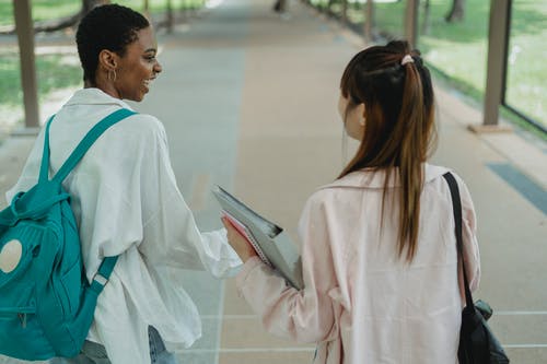 性格开朗的多民族女学生在校园人行道上行走和聊天 · 免费素材图片