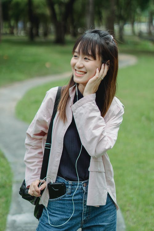 亚裔女子带着耳机在公园 · 免费素材图片