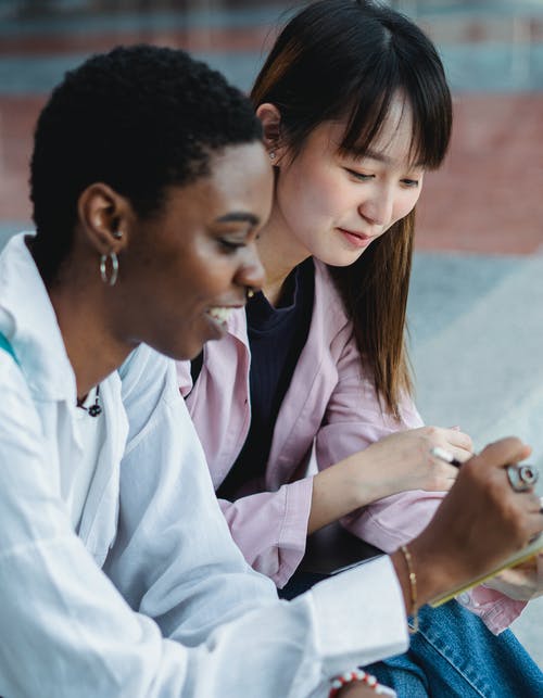 作物微笑多样化的女朋友聊天，同时在大街上学习 · 免费素材图片