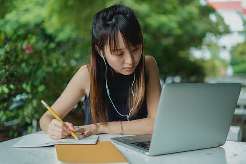 有膝上型计算机和笔记本的被聚焦的妇女 · 免费素材图片