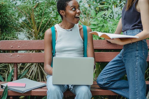 自然界中使用计算机和笔记本时聊天的多种族妇女 · 免费素材图片