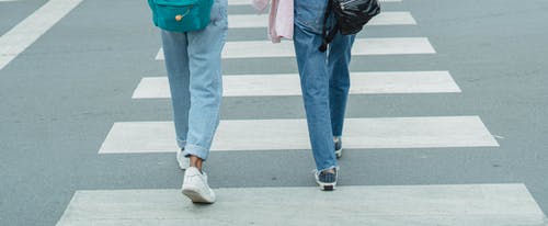 无法认出的女人，穿着牛仔裤穿越城市的街道 · 免费素材图片
