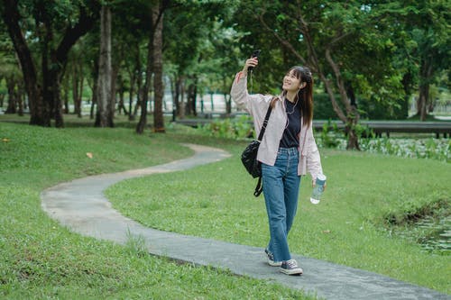 微笑的女士在公园里采取自拍照 · 免费素材图片