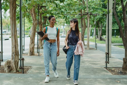 沿着小巷走的开朗多样的女人 · 免费素材图片