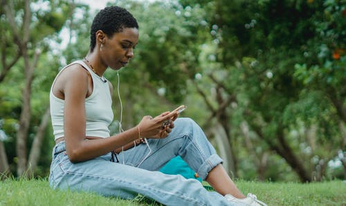 有智能手机的集中的黑人妇女在草坪 · 免费素材图片