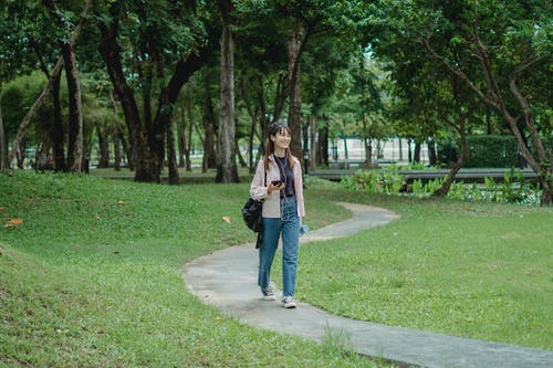 性格开朗的年轻女子，在公园散步 · 免费素材图片