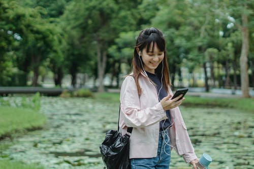 有智能手机和耳机的正面种族妇女 · 免费素材图片