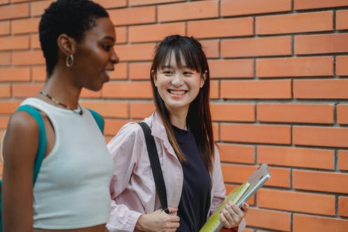 快乐的多民族学生聊天，并在砖瓦房外面 · 免费素材图片