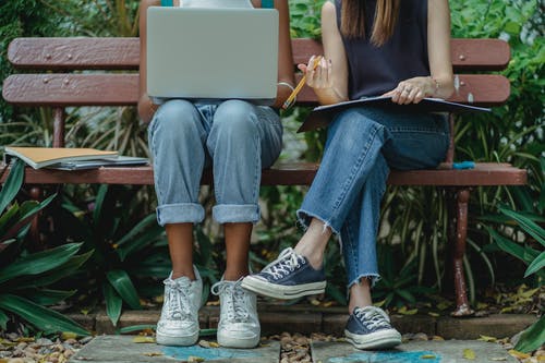 不同的学生在长凳上使用笔记本电脑进行团队合作 · 免费素材图片