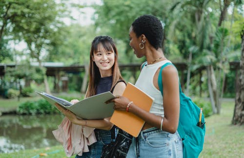 多种族的女性朋友在公园里用记事本散步时说话 · 免费素材图片