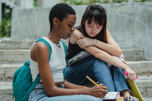 多种族的女学生坐在楼梯上，一起学习 · 免费素材图片