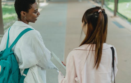 裁剪黑人学生在路面上与匿名女友交谈 · 免费素材图片