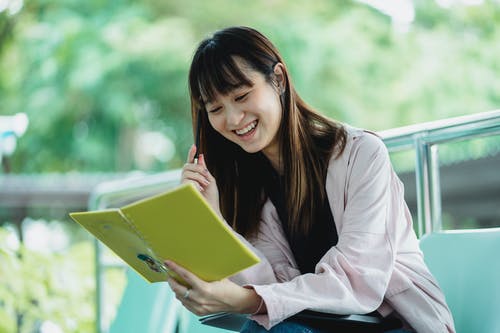 有练习本的正面亚裔学生学习在街道上的 · 免费素材图片