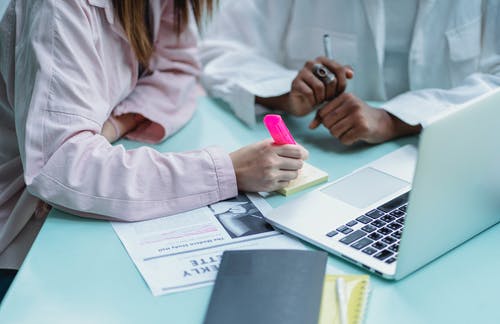 不露面的多种族女友在笔记本电脑附近突出显示记事本贴纸 · 免费素材图片