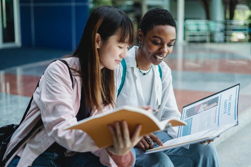 微笑多样的学生在城市楼梯上学习时分享书 · 免费素材图片