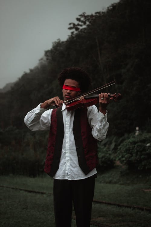 黑蒙住眼睛的音乐家表演拉小提琴的性质 · 免费素材图片