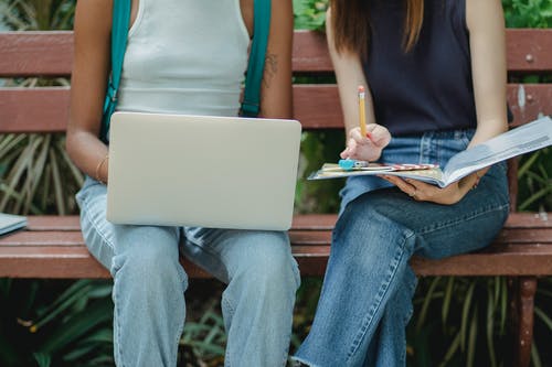 作物不露面多种族的女学生在长凳上使用笔记本电脑 · 免费素材图片