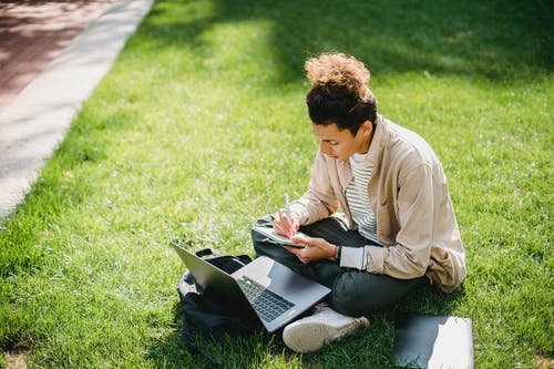认真的人，使用笔记本电脑和在记事本中记笔记 · 免费素材图片