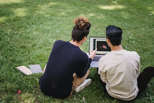 无法识别的男人，在草地上的笔记本电脑上工作 · 免费素材图片