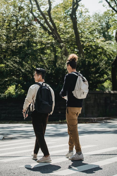 放学后在阳光下走在人行横道上的面目全非的时尚男人 · 免费素材图片