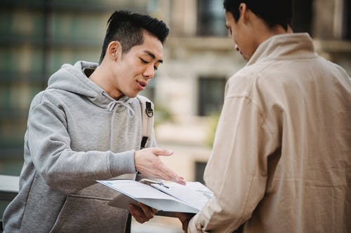 灰色连帽衫阅读书中的男人 · 免费素材图片