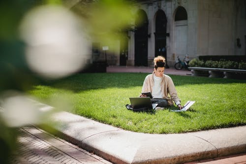 集中在大学校园里的草坪上学习的族裔人 · 免费素材图片