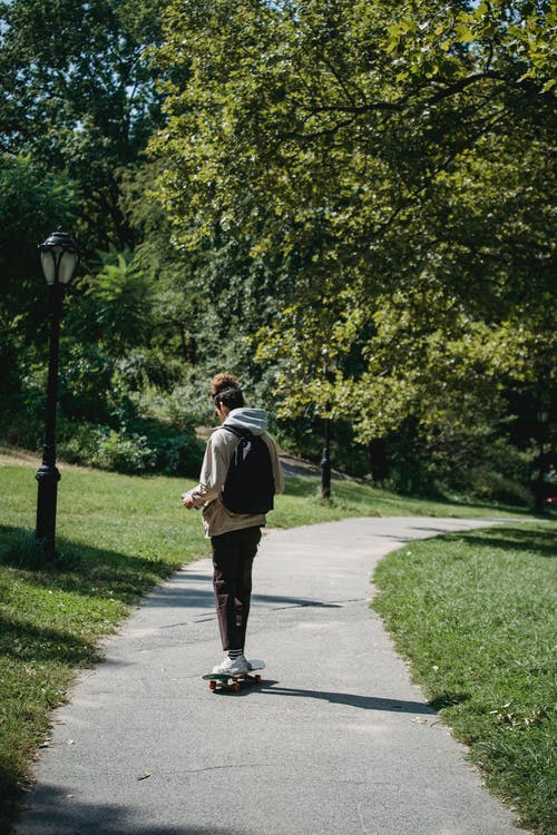 匿名活跃男性骑滑板在公园 · 免费素材图片