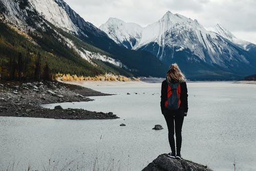 旅行者欣赏雪山环抱的湖泊 · 免费素材图片