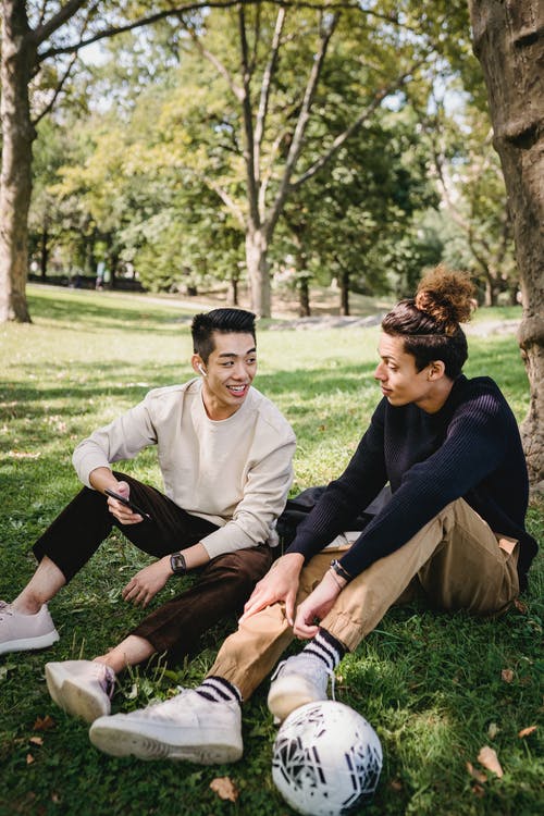 性格开朗的族裔男子在公园的草坪上聊天 · 免费素材图片