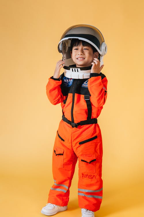 橙色和黑色外套戴头盔的男孩 · 免费素材图片
